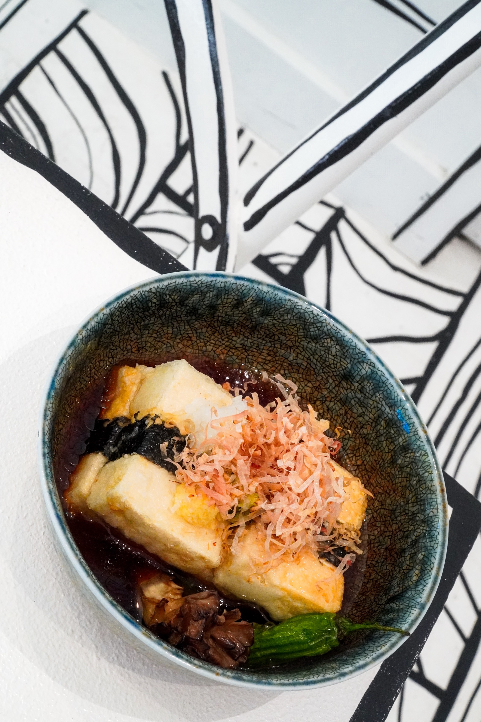 A Shirokuro dish served against black-and-white line art